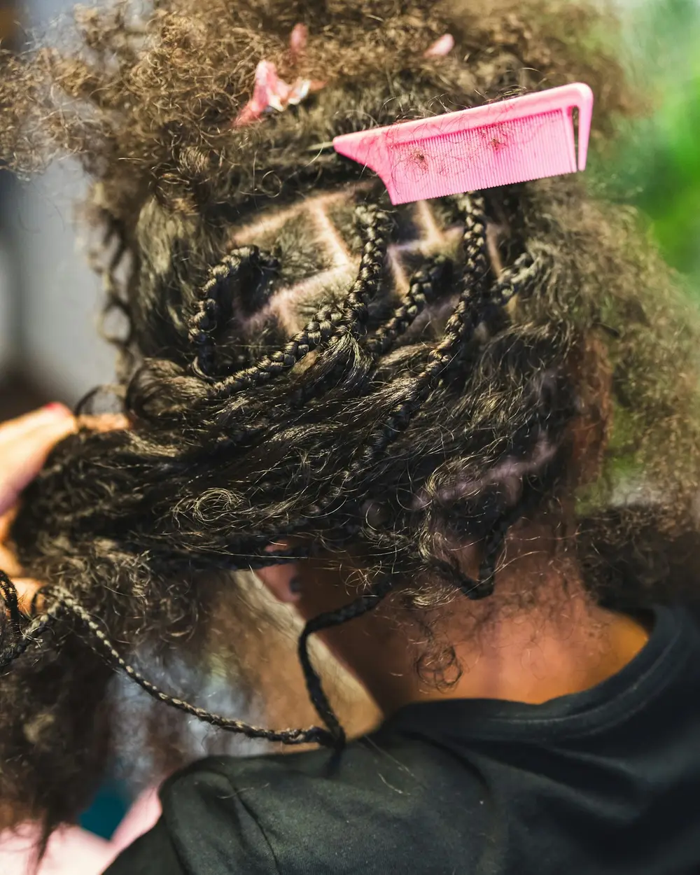 Une coiffeuse tresse des cheveux bouclés.